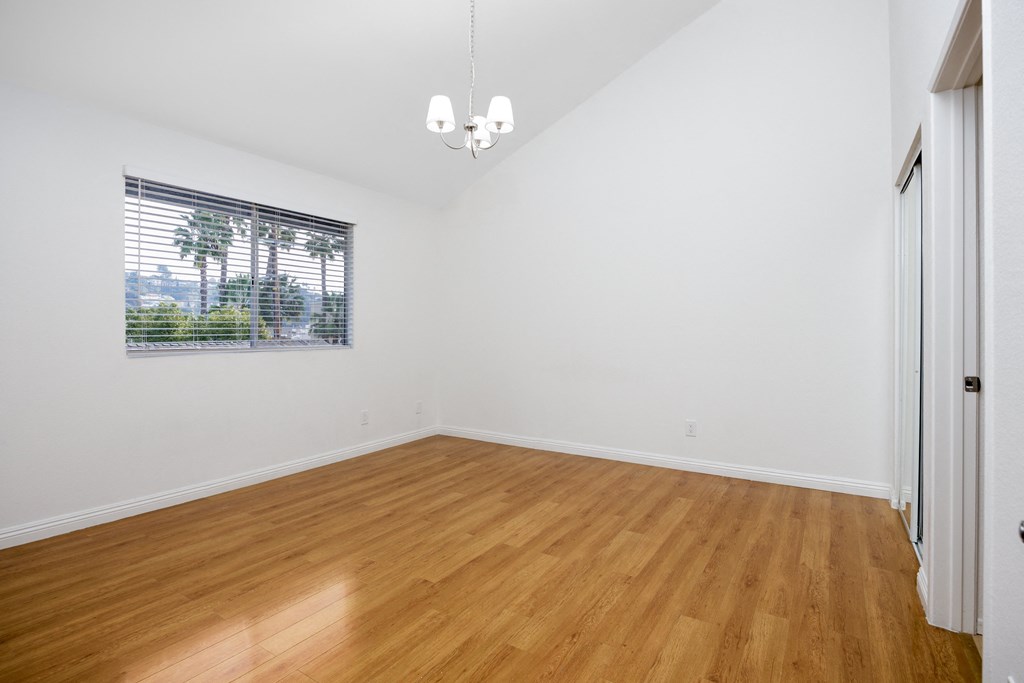 an empty living room with wood floors and a window