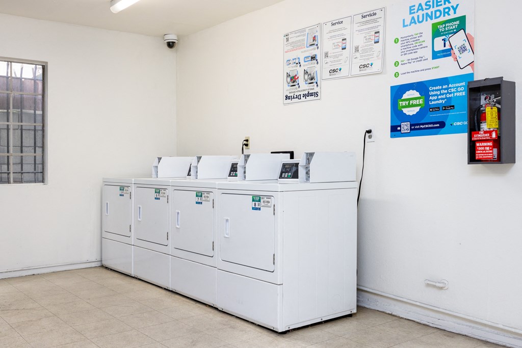a laundry room with four washers and a row of washing machines