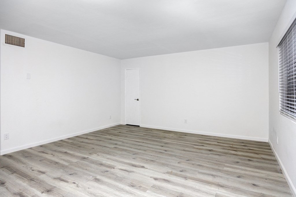 an empty room with white walls and wood floors