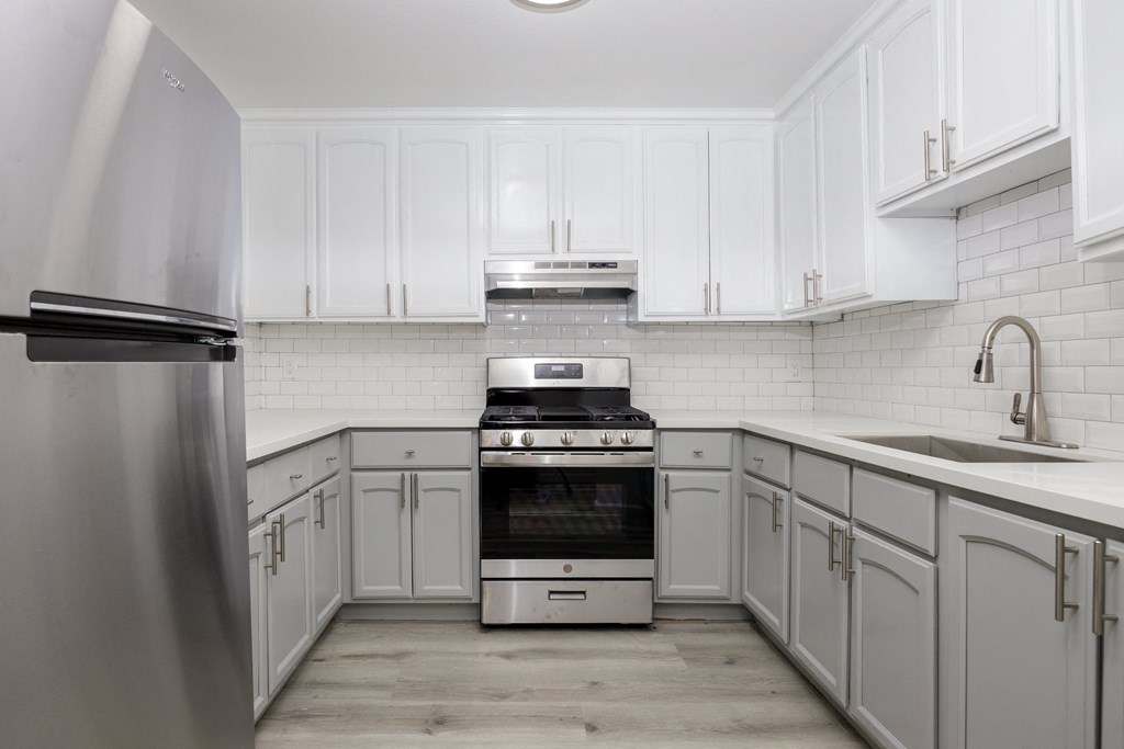 a white kitchen with white cabinets and stainless steel appliances