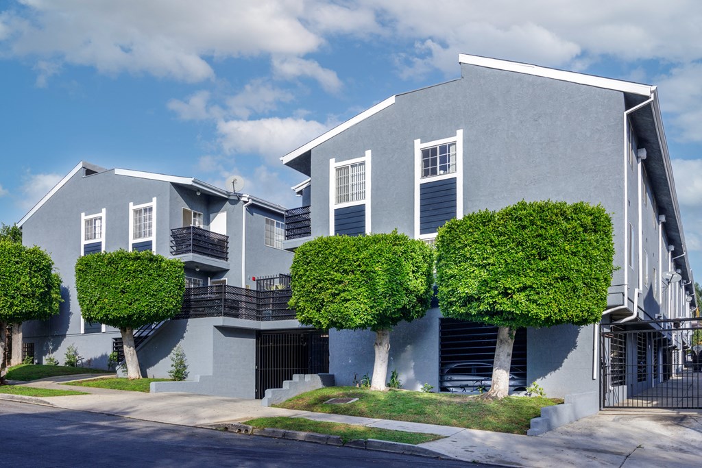a blue and white house with three trees in front of it