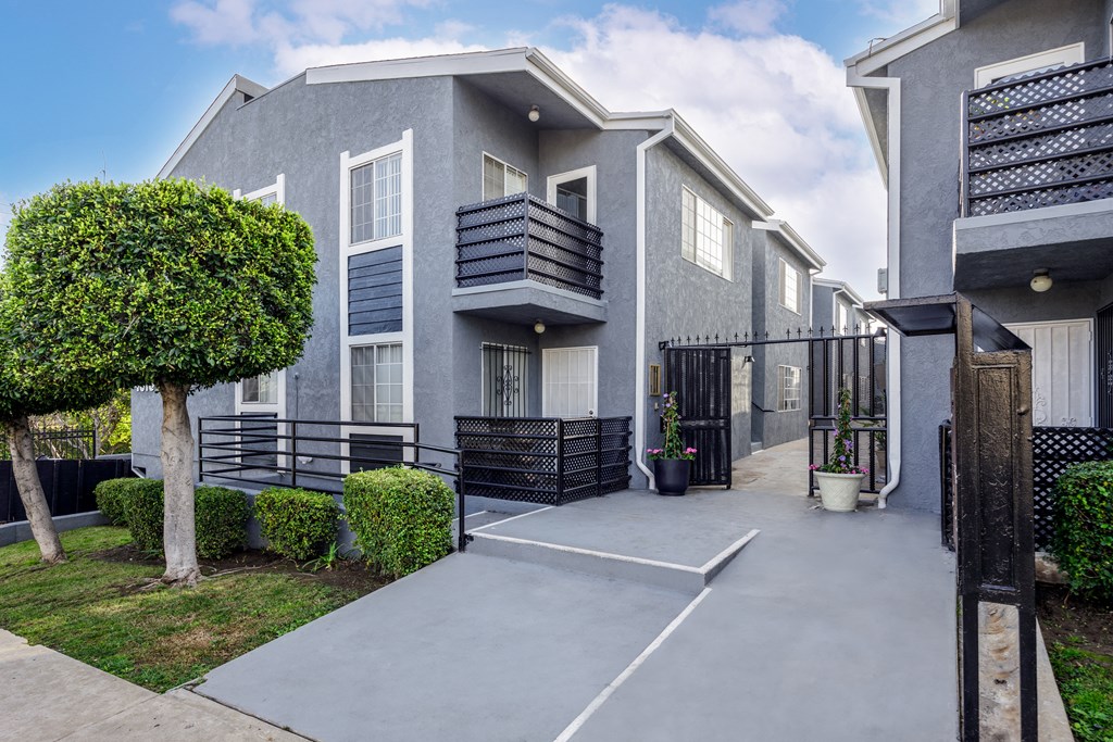 a grey building with a driveway and a tree in front of it