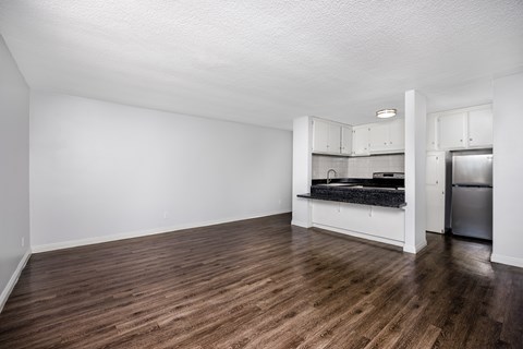 A kitchen with a stainless steel refrigerator and wooden floors.