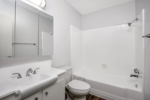 A white bathroom with a toilet, sink, and bathtub.
