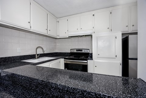 A kitchen with white cabinets and a black granite countertop.