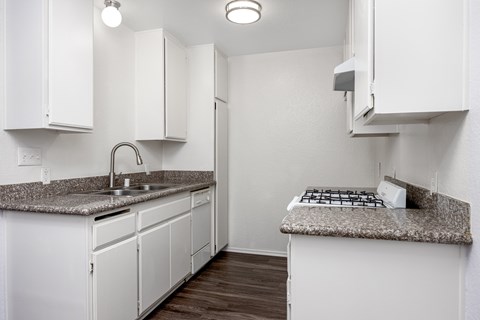 A kitchen with white cabinets and a granite countertop.