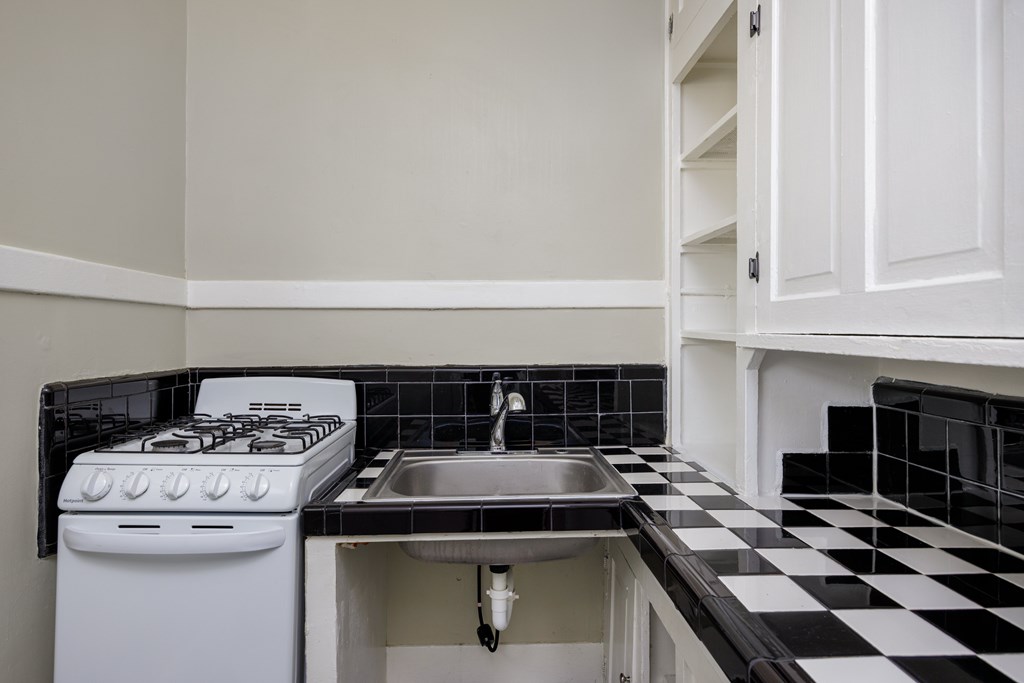 a kitchen with black and white checkered floor and a stove and sink