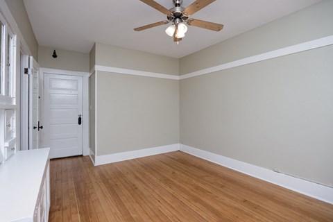 an empty living room with wooden floors and a ceiling fan