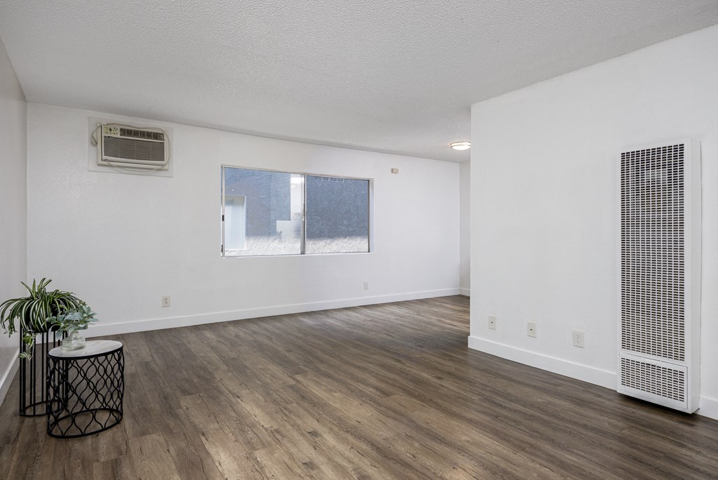 the living room and dining room of an apartment with white walls and wood floors