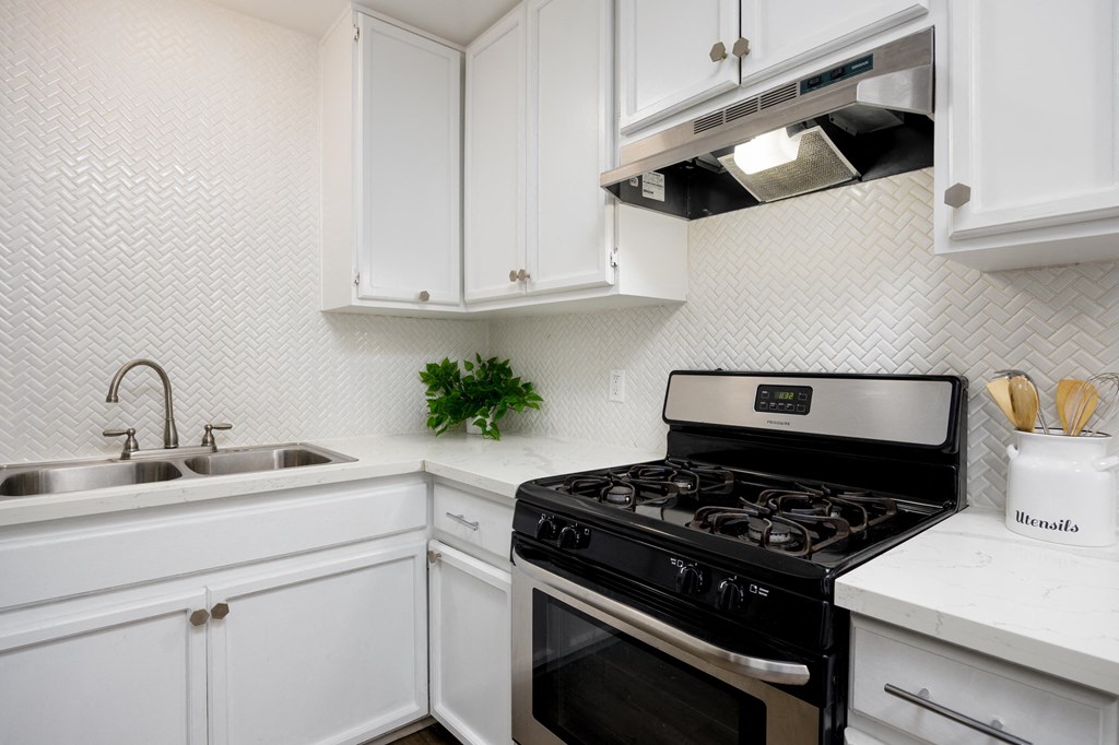 a white kitchen with a stove and a sink