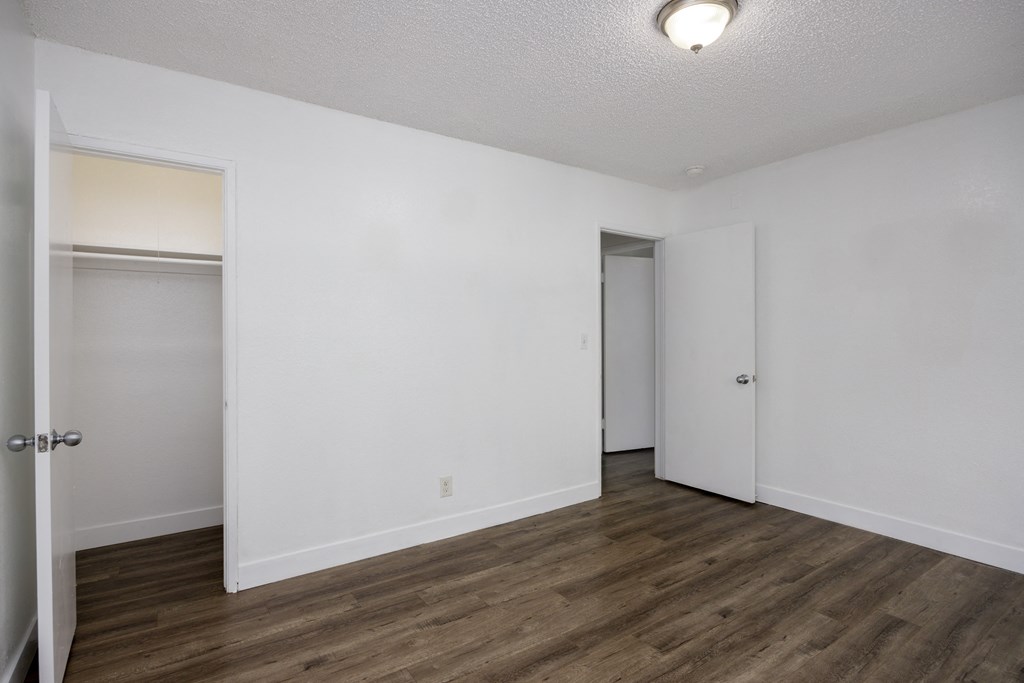an empty bedroom with white walls and wood flooring