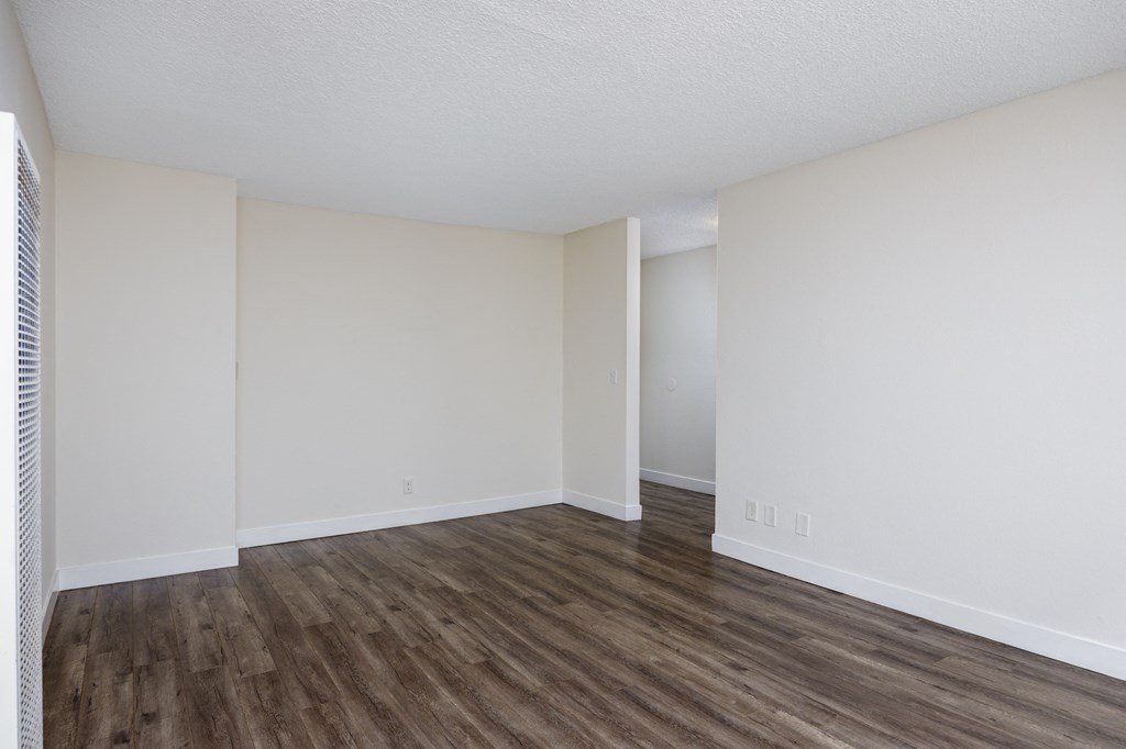 an empty living room with white walls and wood flooring