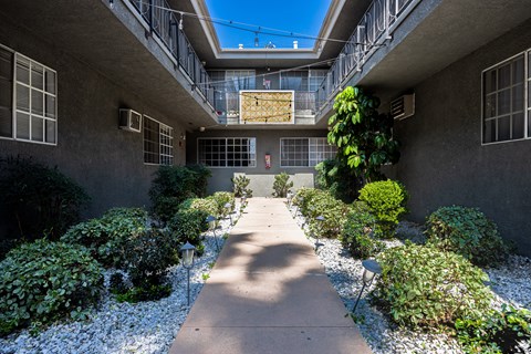 the courtyard of an apartment building with a walkway and plants