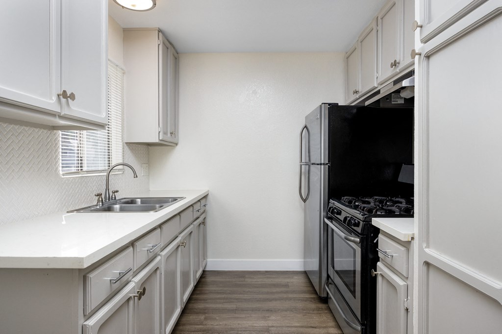an empty kitchen with white cabinets and a black stove and refrigerator