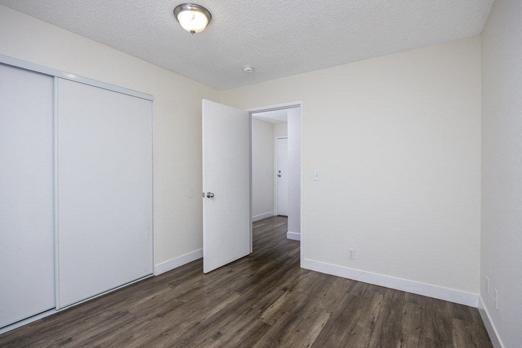 an empty bedroom with white walls and wood flooring