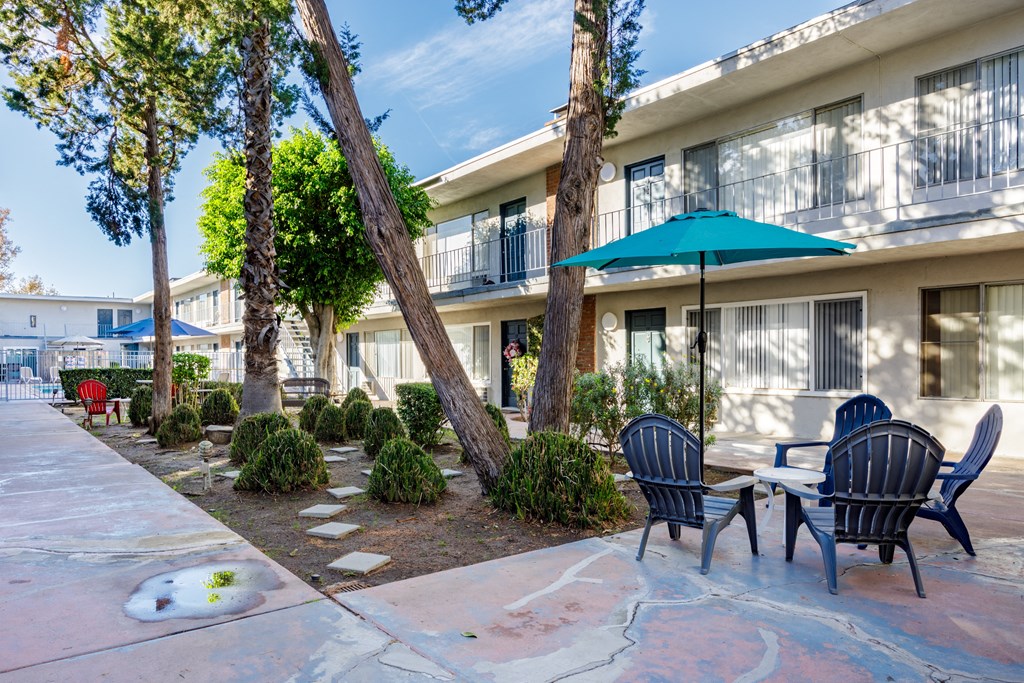 a patio with chairs and umbrellas in front of a building