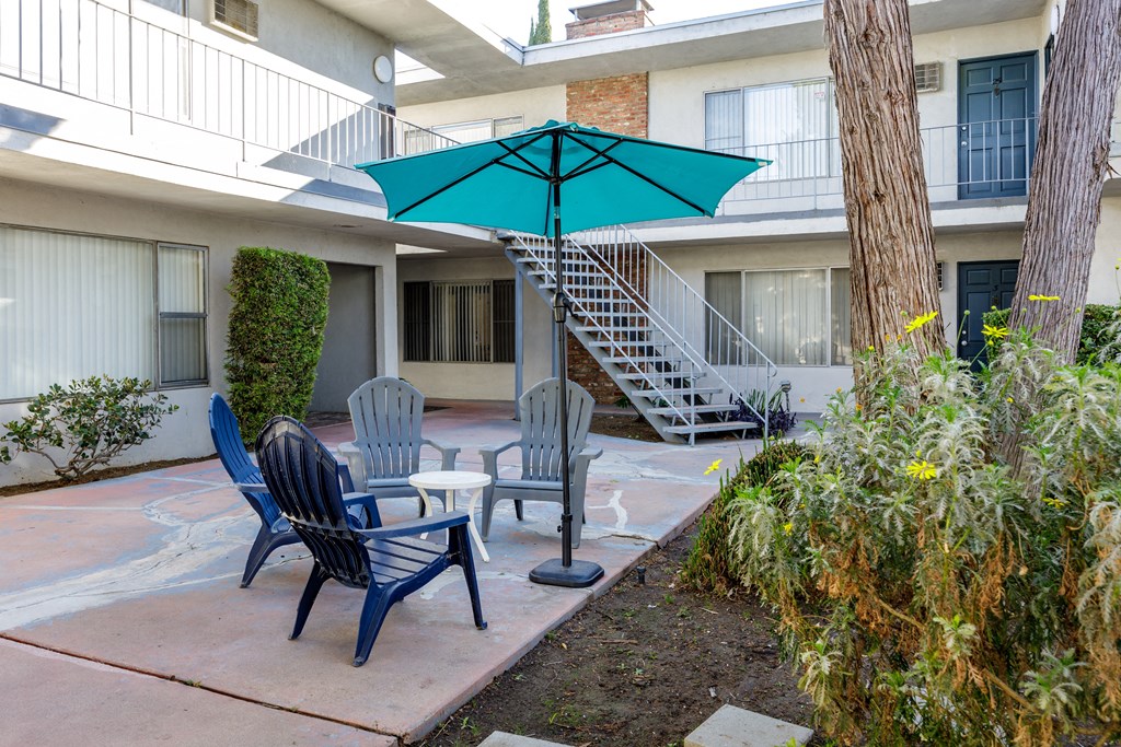 a patio with chairs and an umbrella in front of a building