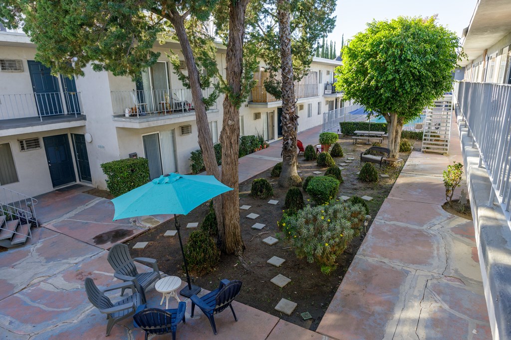 a courtyard with a blue umbrella and tables and chairs