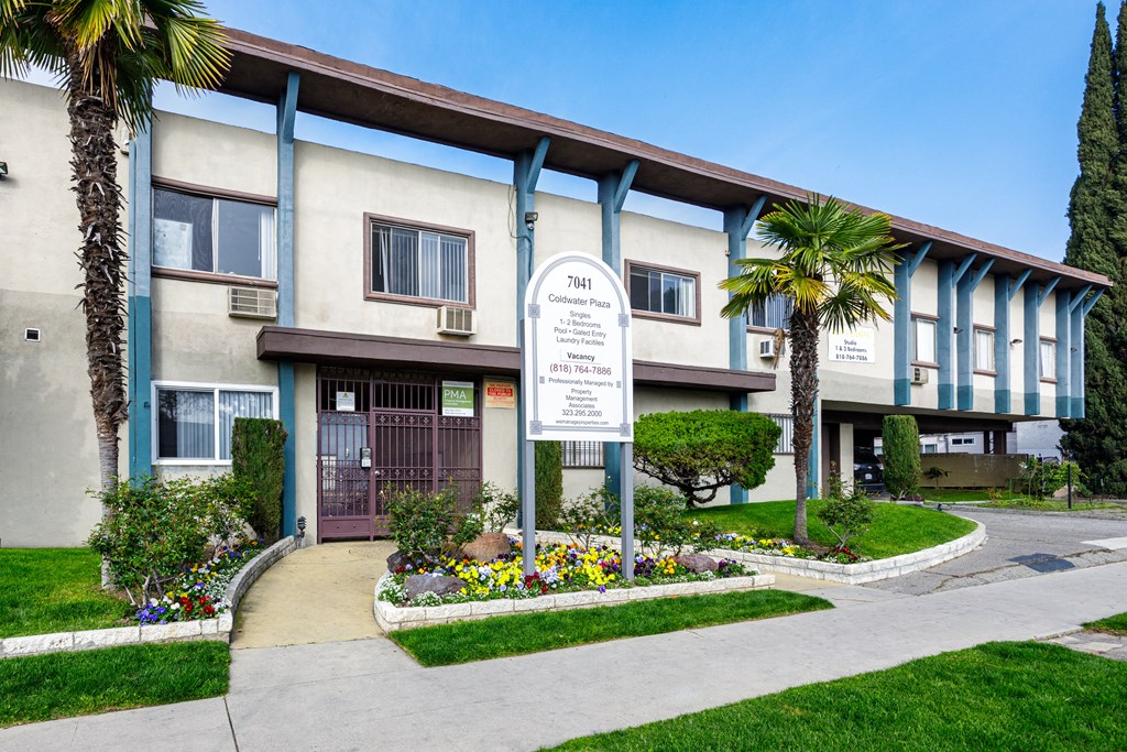 a building with a sign and flowers in front of it