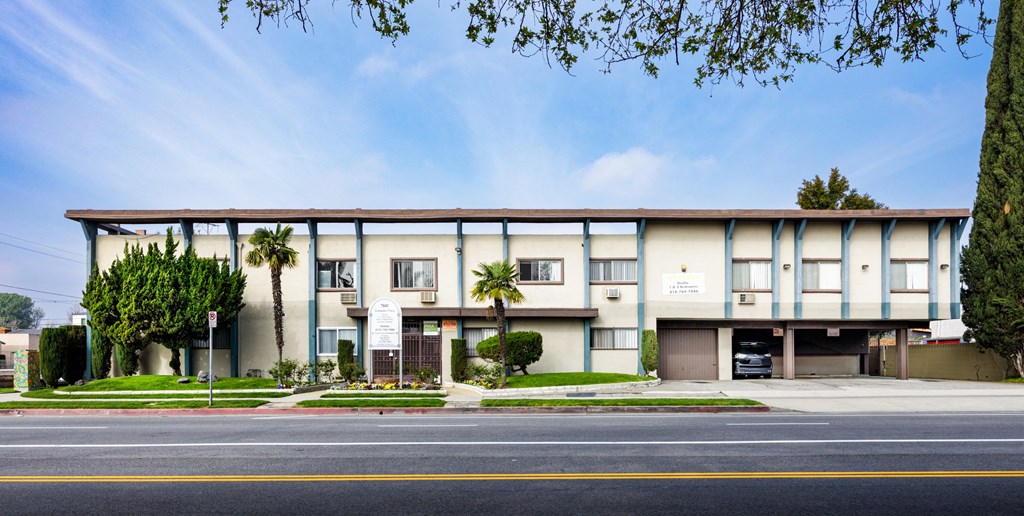 a large building with palm trees in front of it on a street