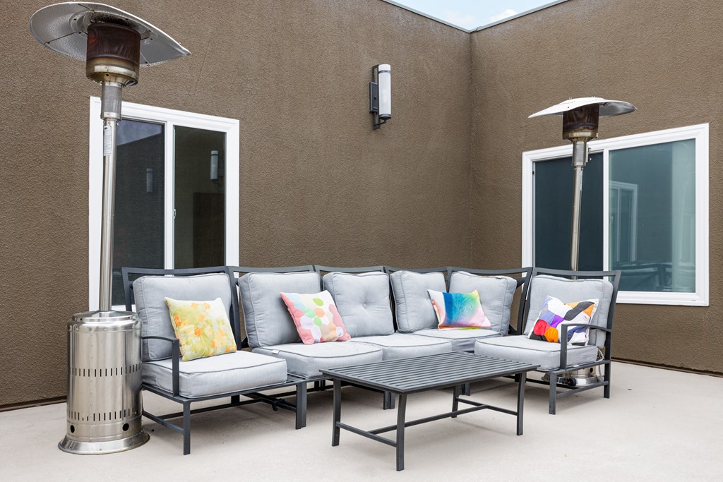 a patio with couches and tables outside of a building