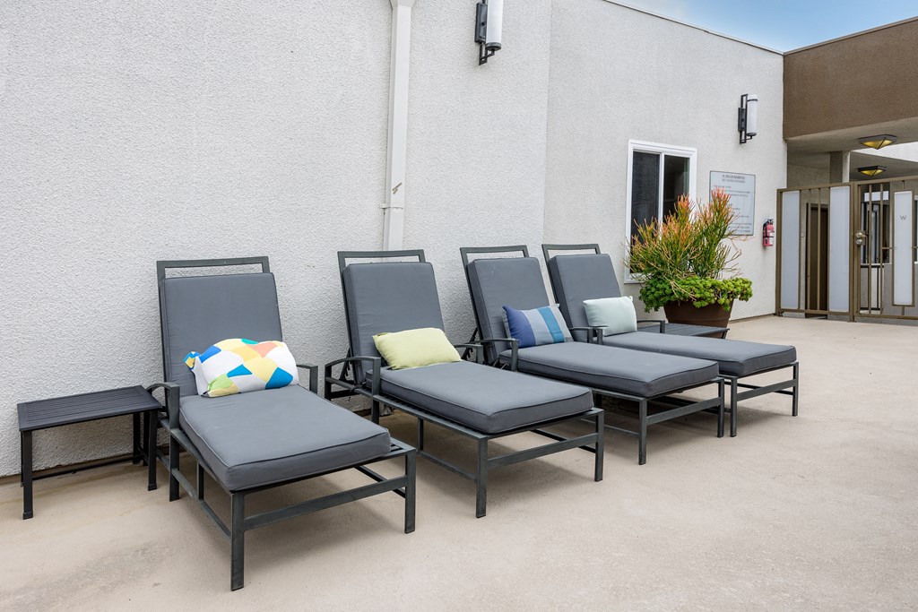 a row of chairs outside of a building with pillows