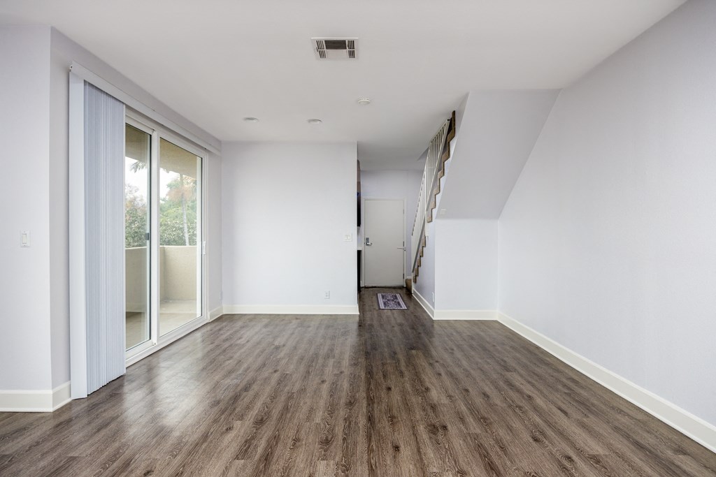 an empty living room with white walls and wood floors