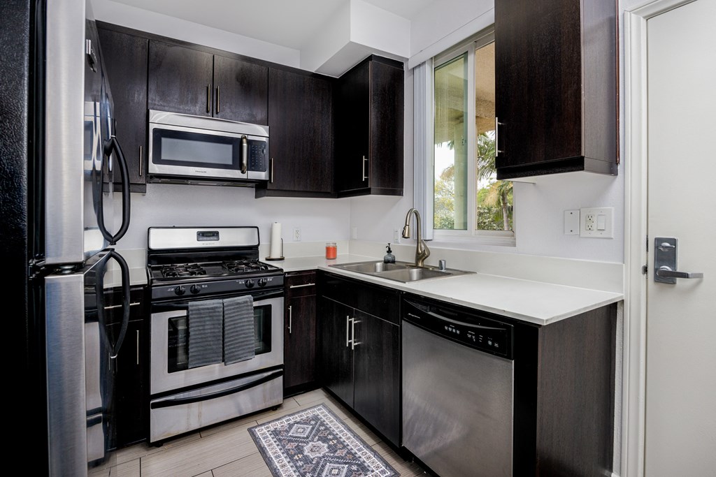 a kitchen with black cabinets and stainless steel appliances and a window