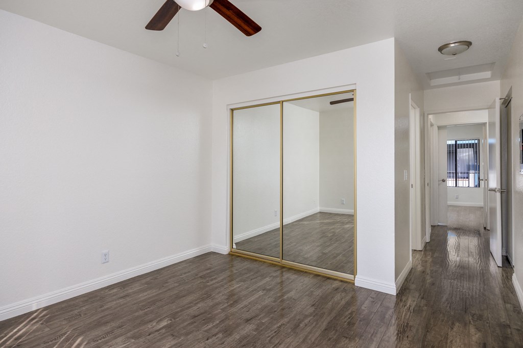 an empty room with a ceiling fan and a mirrored closet