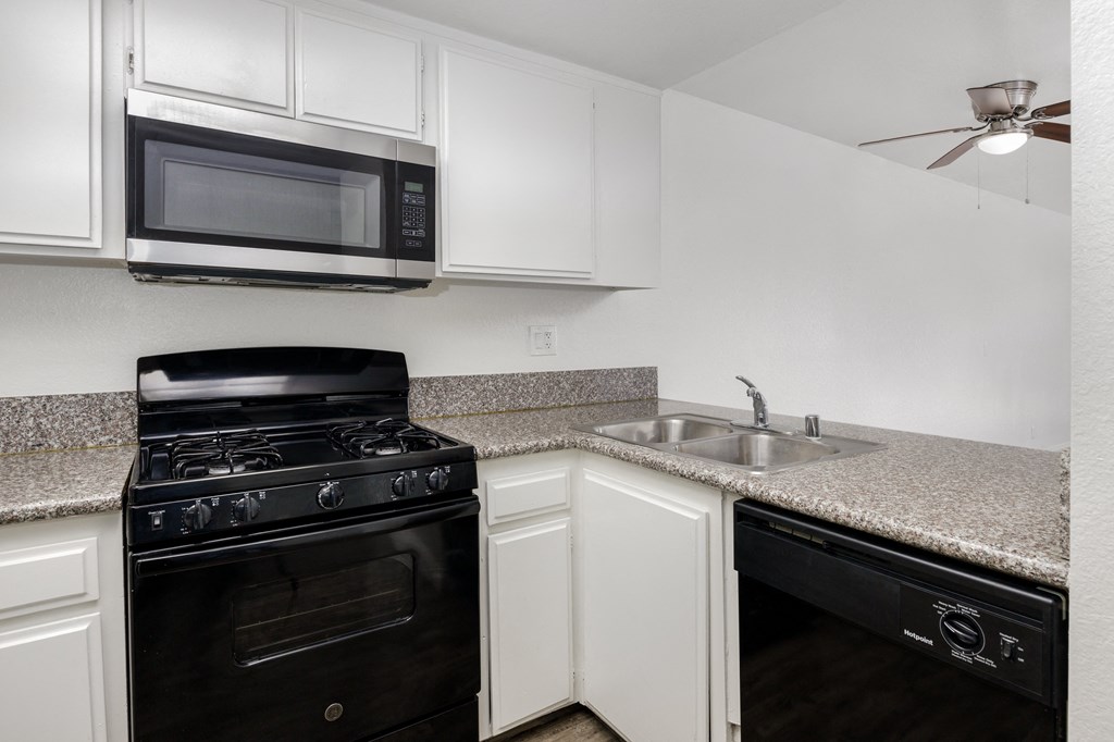a kitchen with white cabinets and black appliances and a granite counter top