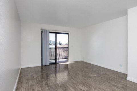 an empty living room with a sliding glass door to a balcony