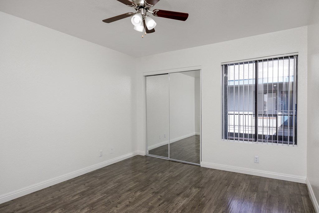 an empty living room with a ceiling fan and a window