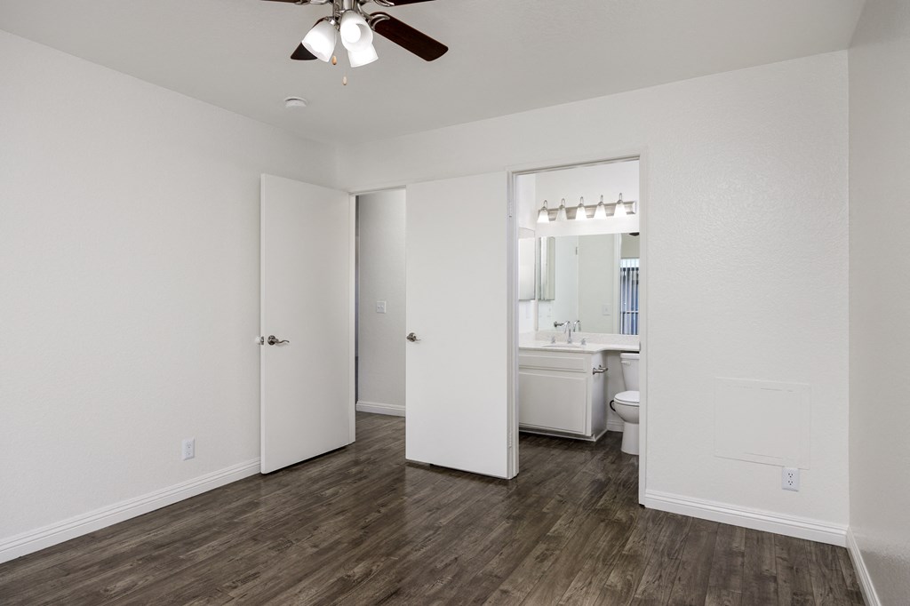 an empty bedroom with a ceiling fan and a bathroom