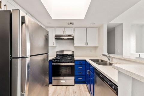 A modern kitchen with a stainless steel refrigerator and blue cabinets.