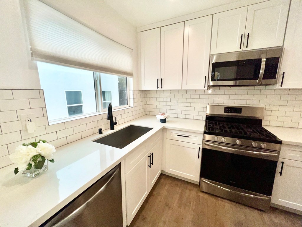 a white kitchen with stainless steel appliances and white cabinets