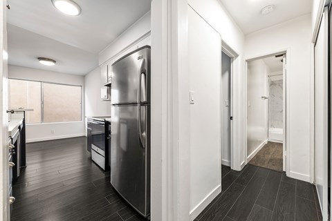 A modern kitchen with a stainless steel refrigerator and wooden floors.