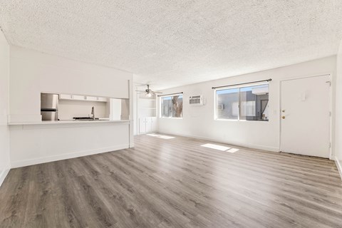 A spacious room with wooden flooring and white walls.