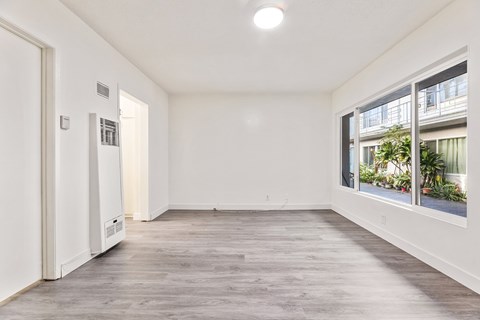A spacious room with a window overlooking a balcony with plants.