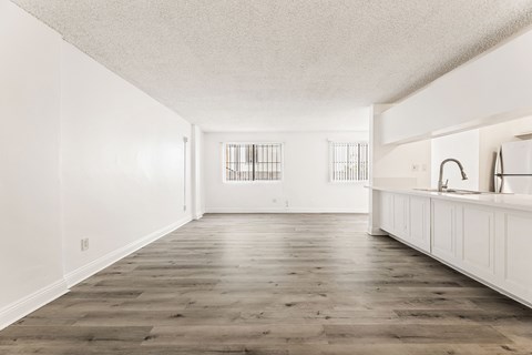 A spacious kitchen with white cabinets and a wooden floor.