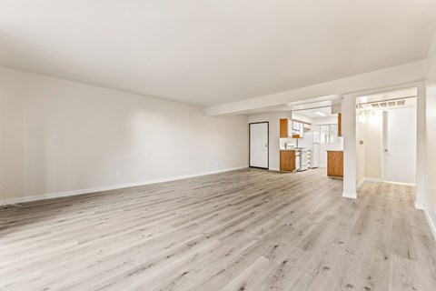A spacious room with wooden flooring and white walls.