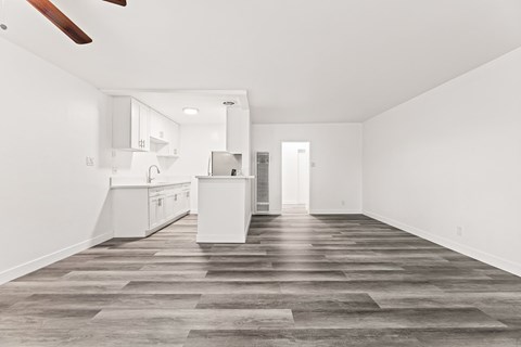 A spacious kitchen with white cabinets and a wooden floor.