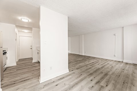 A white room with wooden floors and a doorway leading to another room.