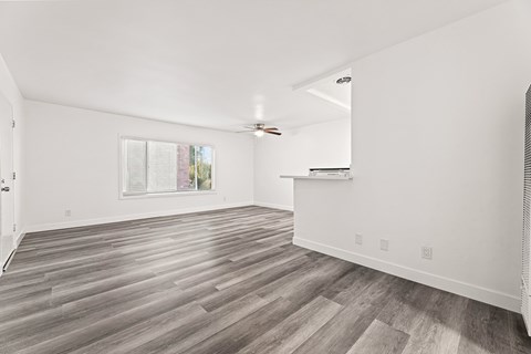 A spacious room with wooden flooring and white walls.