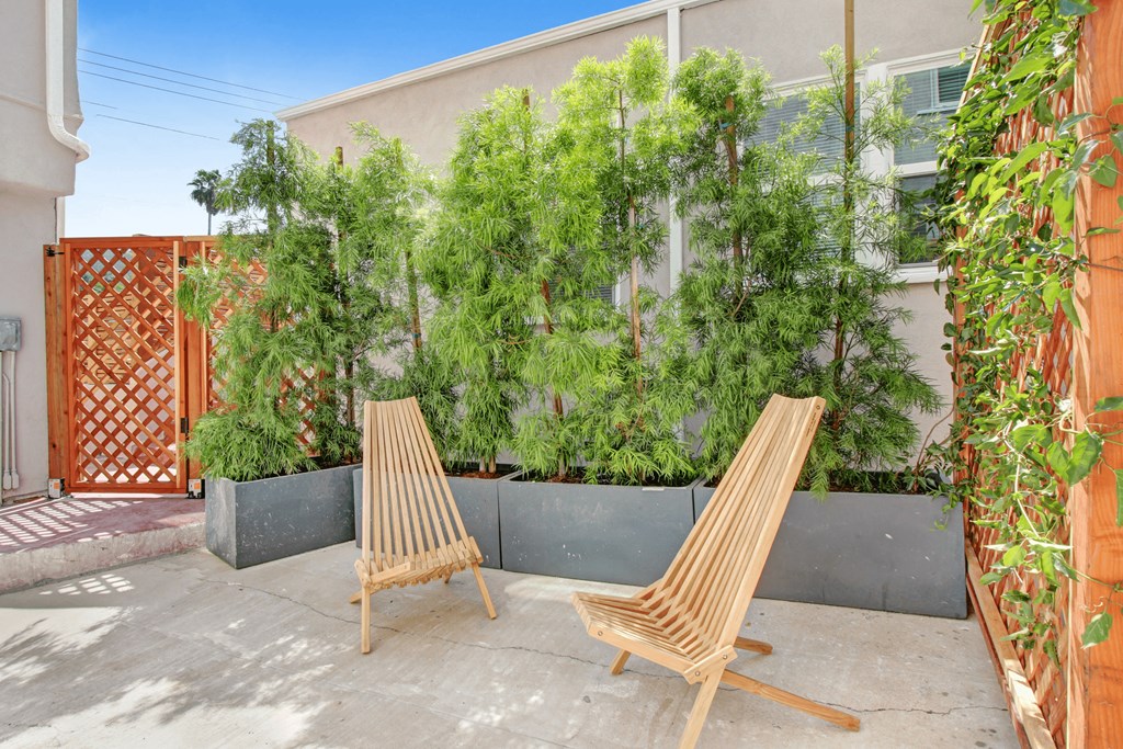 two wooden chairs on a patio next to a garden