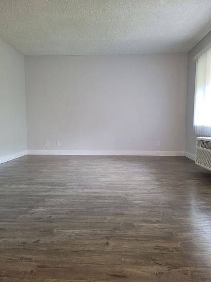 an empty living room with wooden floors and a window