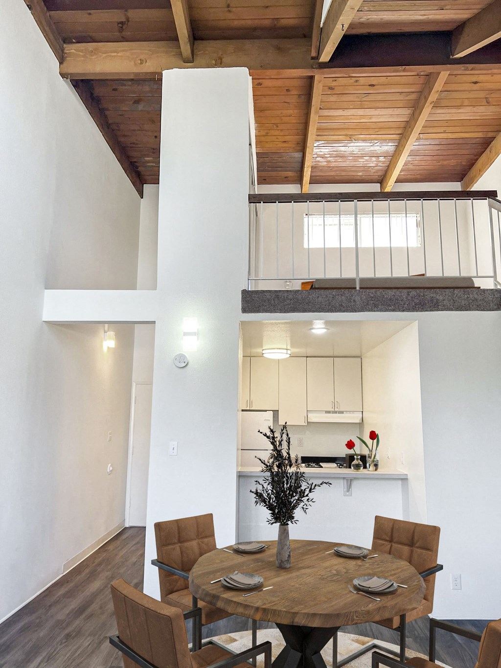 a dining area with a wooden table and chairs and a kitchen in the background