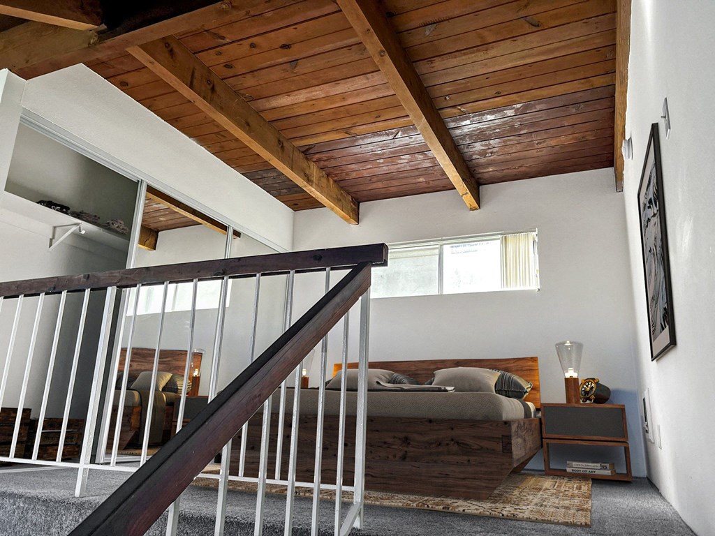 a lofted bedroom with a bed and a wooden ceiling