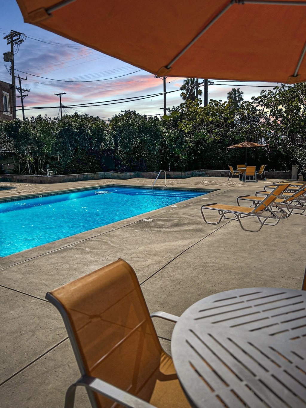 a swimming pool with chairs and an umbrella next to it