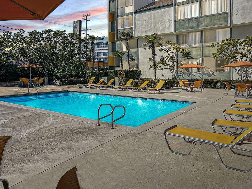 a swimming pool at a hotel with yellow lounge chairs