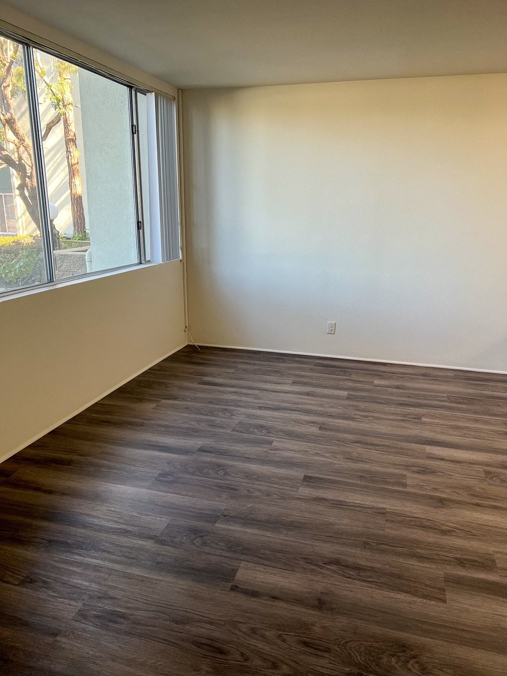 an empty living room with wood floors and a window